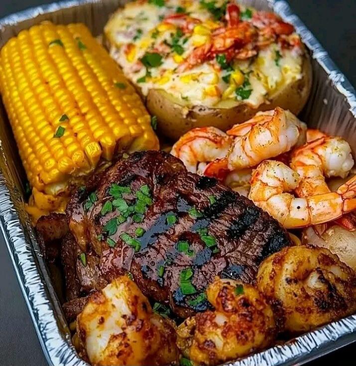 Grilled corn on the cob, shrimp, a juicy steak topped with herbs, roasted potatoes, and a loaded baked potato with vegetables and cheese.