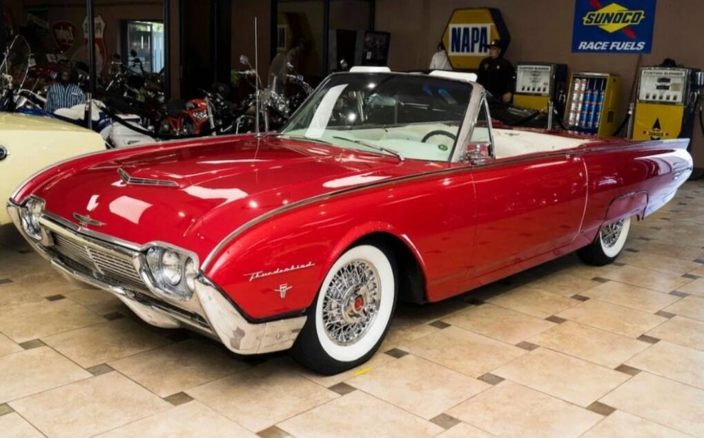 Vintage red convertible car on showroom floor.