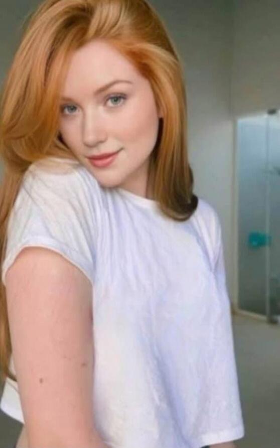 Portrait of a young woman with red hair wearing a white shirt.