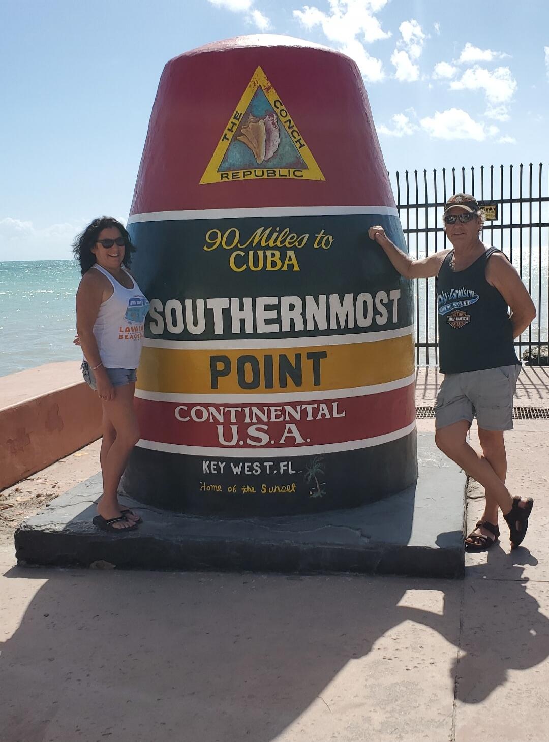 THE CONCH REPUBLIC 90 Miles to CUBA SOUTHERNMOST POINT CONTINENTAL U.S.A. KEY WEST, FL. Home of the Sunset. A woman is wearing a 'LAVA BEACH' shirt, and a man is wearing a 'Harley-Davidson' shirt.
