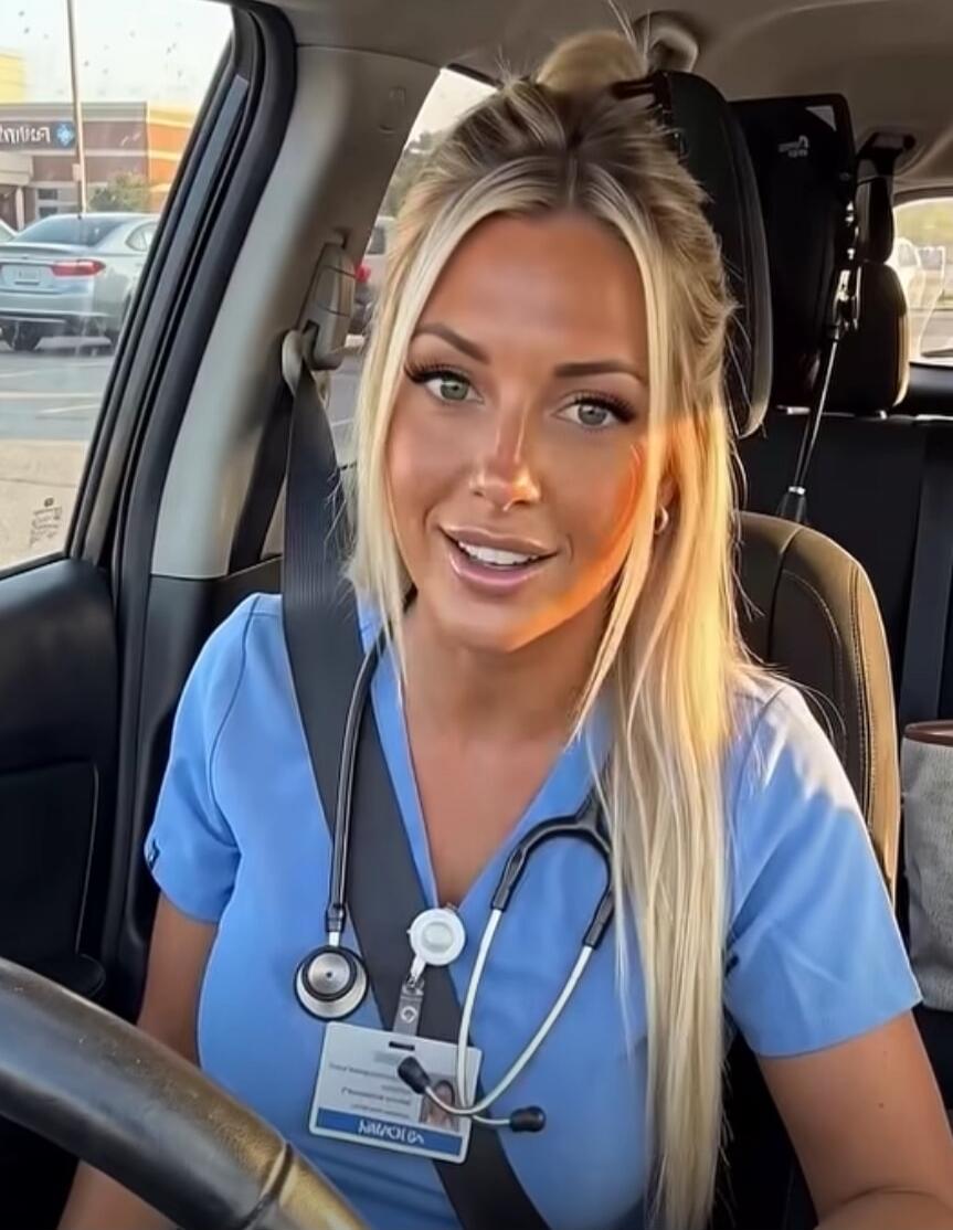 A blonde woman in blue scrubs with a stethoscope around her neck is sitting in a car, smiling at the camera. A name tag with 