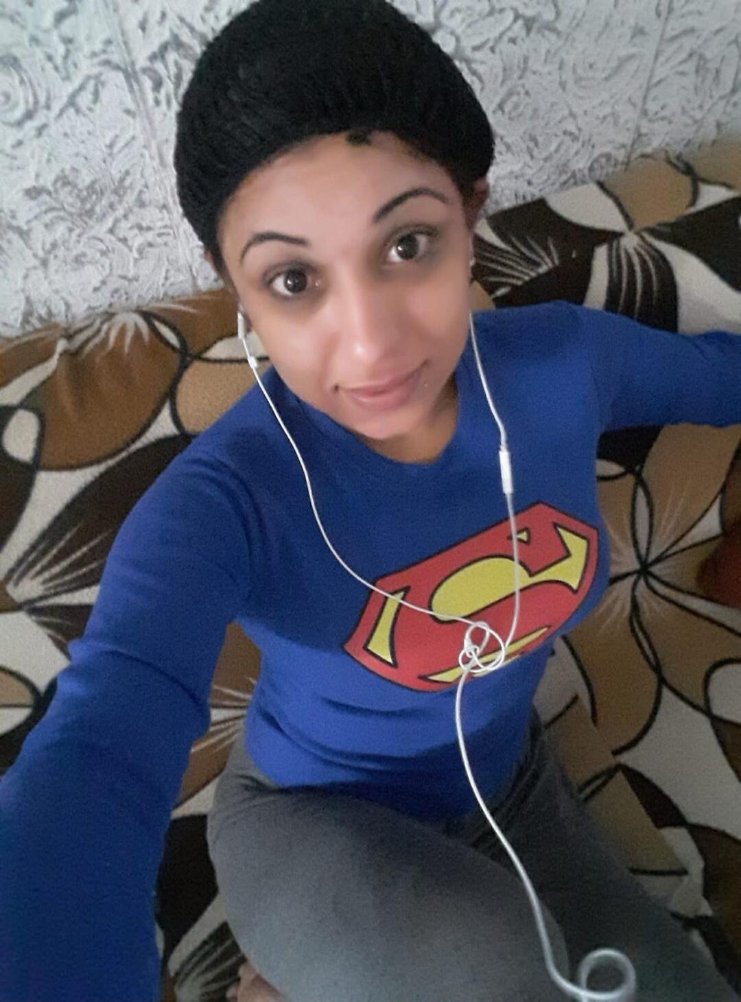 Selfie of a woman wearing a Superman shirt and headphones