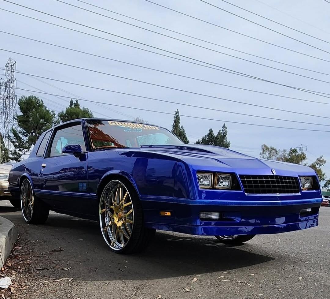 Blue custom classic car with gold rims parked on the street.
