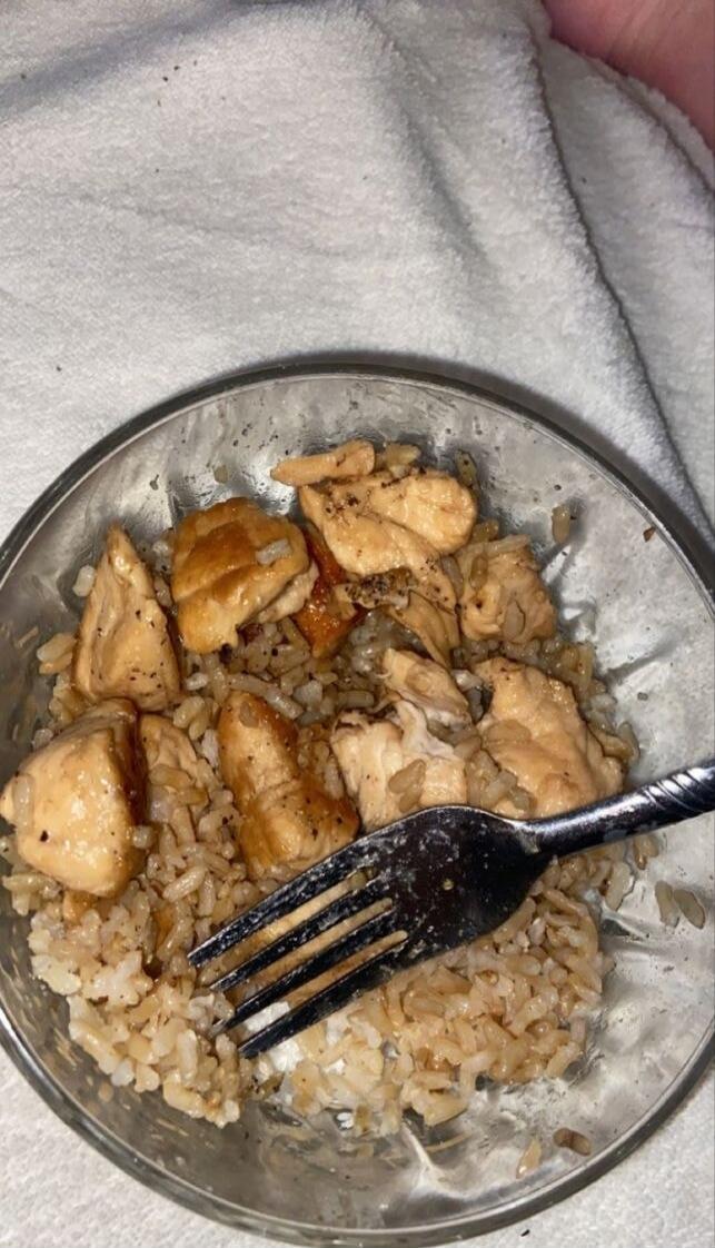 Rice with chicken pieces in a metal bowl with a fork.