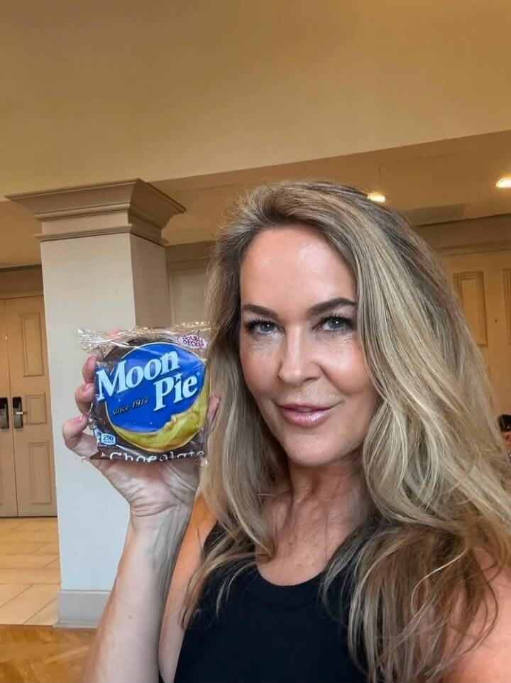 A woman holds a Moon Pie snack. The packaging shows 'Moon Pie since 1917' and 'Chocolate', with '290' calories visible.