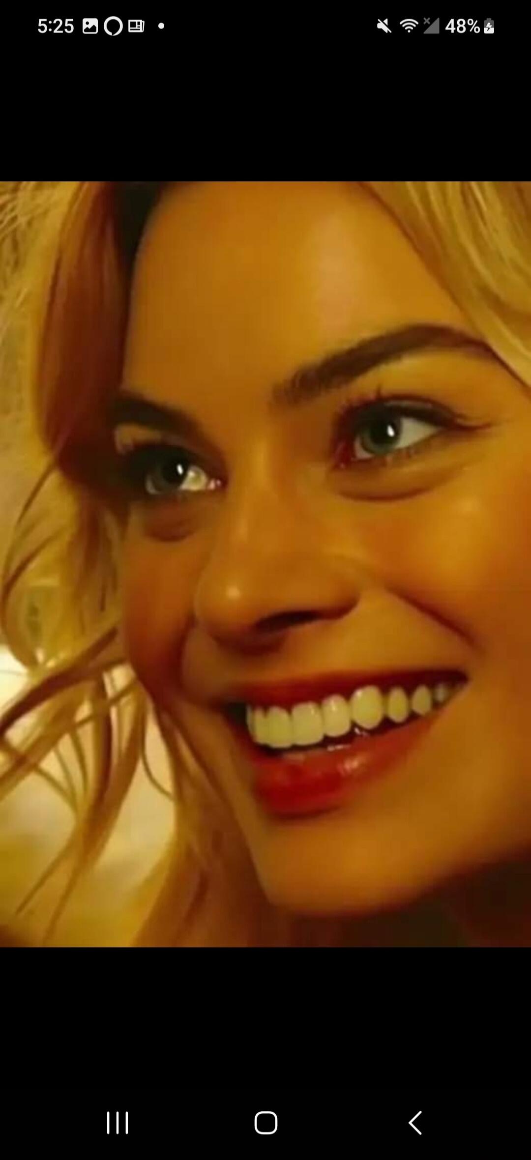 A close-up shot of a smiling woman with blonde hair and blue eyes.