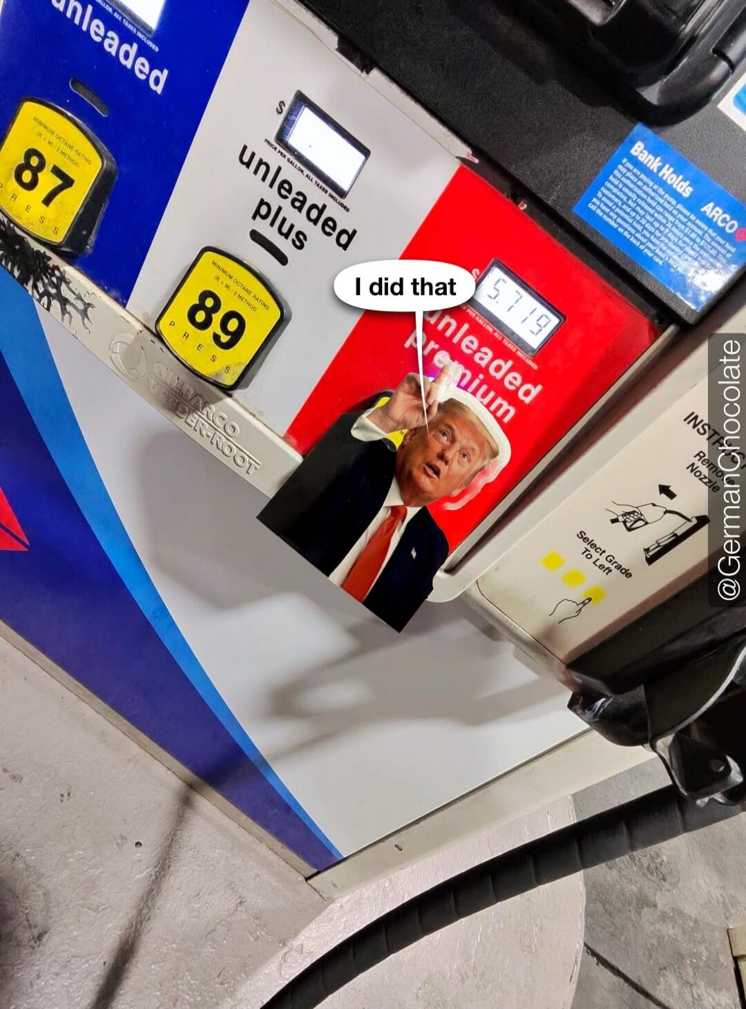 A sticker of Donald Trump pointing at a gas pump's price display, with a speech bubble saying 'I did that'. The gas price shown is $5.719 for unleaded premium fuel. Other visible text includes 'unleaded', 'unleaded plus', '87', '89', 'MINIMUM OCTANE RATING (R+M)/2 METHOD', 'PRESS', 'PRICE PER GALLON, ALL TAXES INCLUDED', 'Bank Holds ARCO', and inst