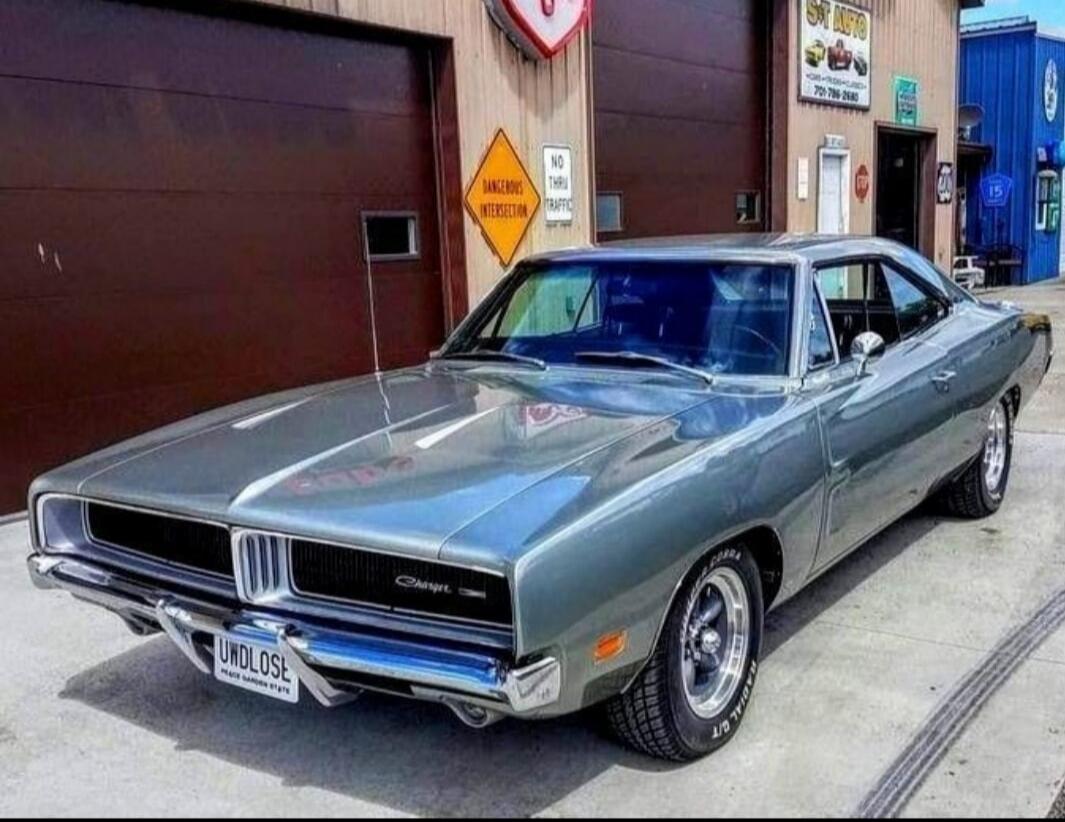 Vintage blue-gray Dodge Charger parked on a street with a chrome bumper, visible 'Charger' badge on the grille.