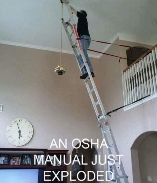 AN OSHA MANUAL JUST EXPLODED. A person is on a dangerously extended ladder, secured with straps to a railing, attempting to reach a high ceiling fixture. This setup clearly violates safety regulations.