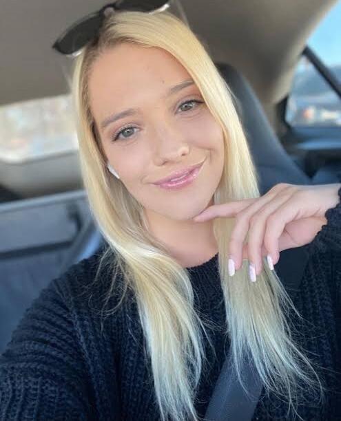 A young blonde woman taking a selfie in a car.