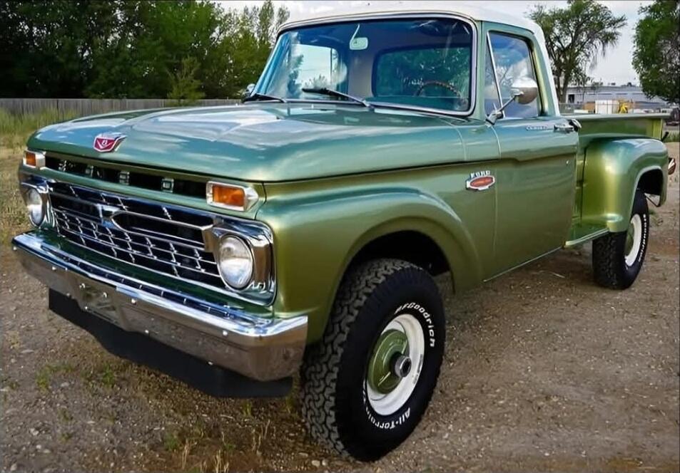 Green vintage pickup truck with chrome bumper, round headlights, and classic grille. Ford emblem visible on the grille; chrome hubcaps; green body with white-wall tires.