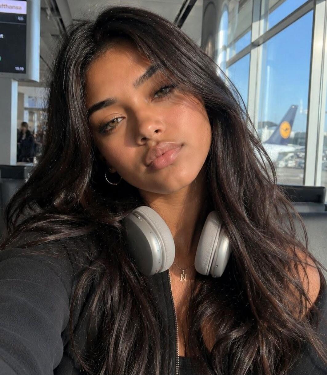 Lufthansa 15:19. A young woman takes a selfie at an airport, with a plane visible outside the window.