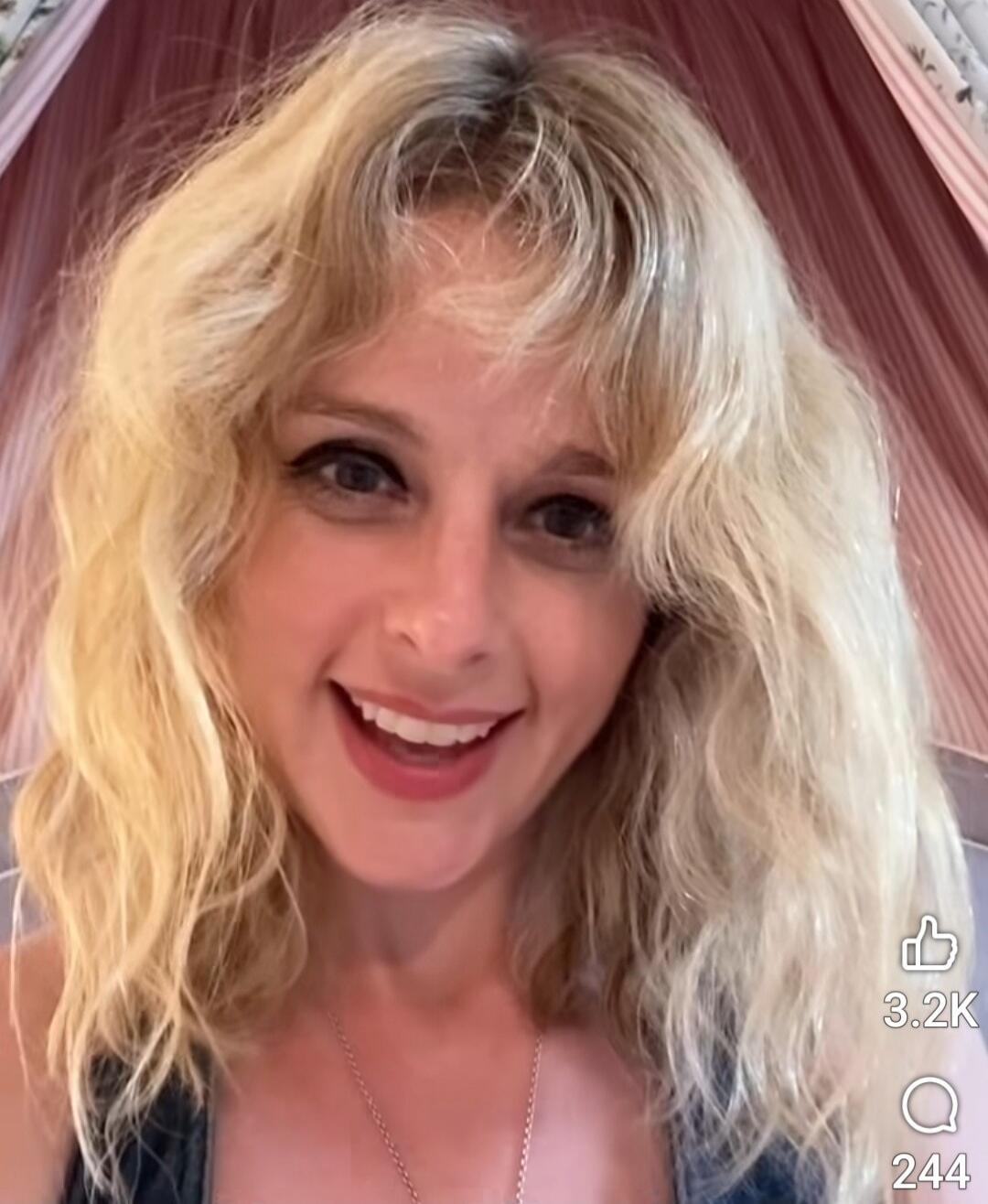 A smiling blonde woman looking at the camera.