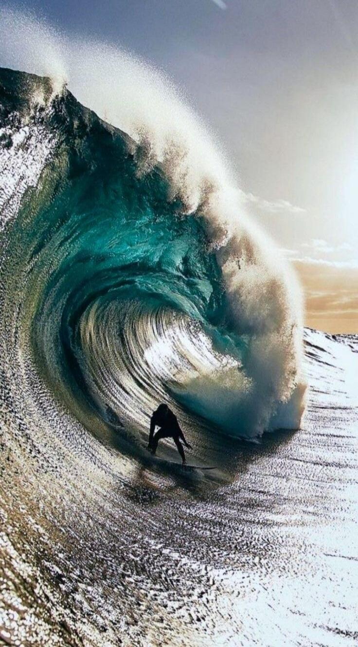 A surfer rides a massive wave, the water forming a powerful tube around them.