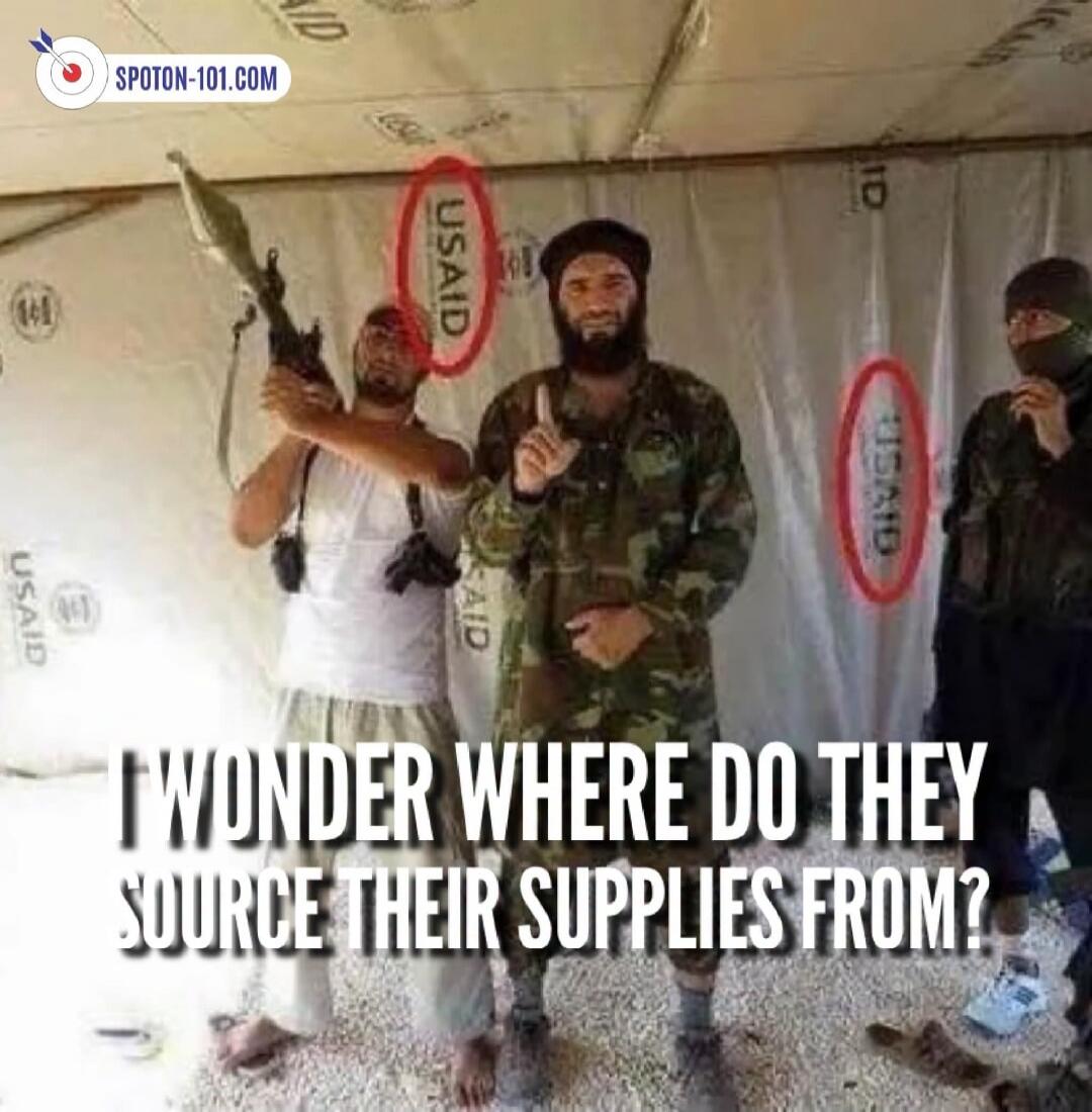 I WONDER WHERE DO THEY SOURCE THEIR SUPPLIES FROM? USAID logos are visible in the background, circled in red, behind three men, two of whom appear to be militants, one holding an RPG.