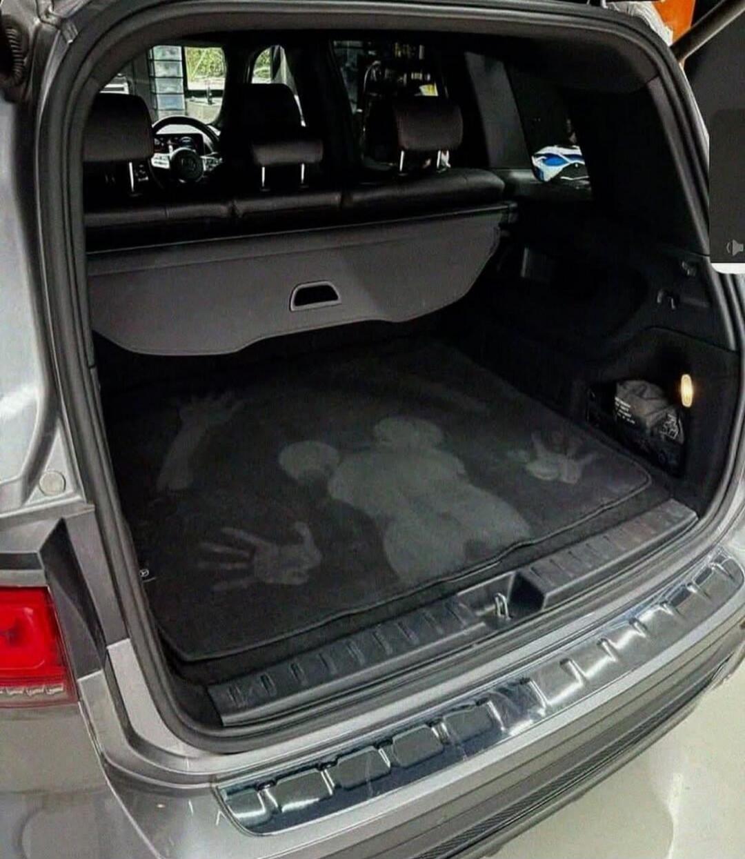 Trunk of an SUV with a mat showing handprint marks.