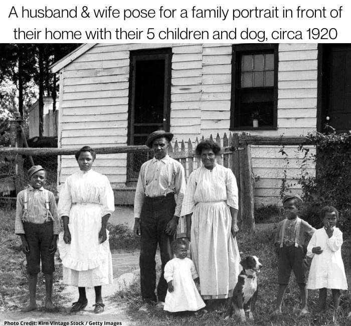 A husband wife pose for a family portrait in front of their home with their 5 children and dog circa 1920
