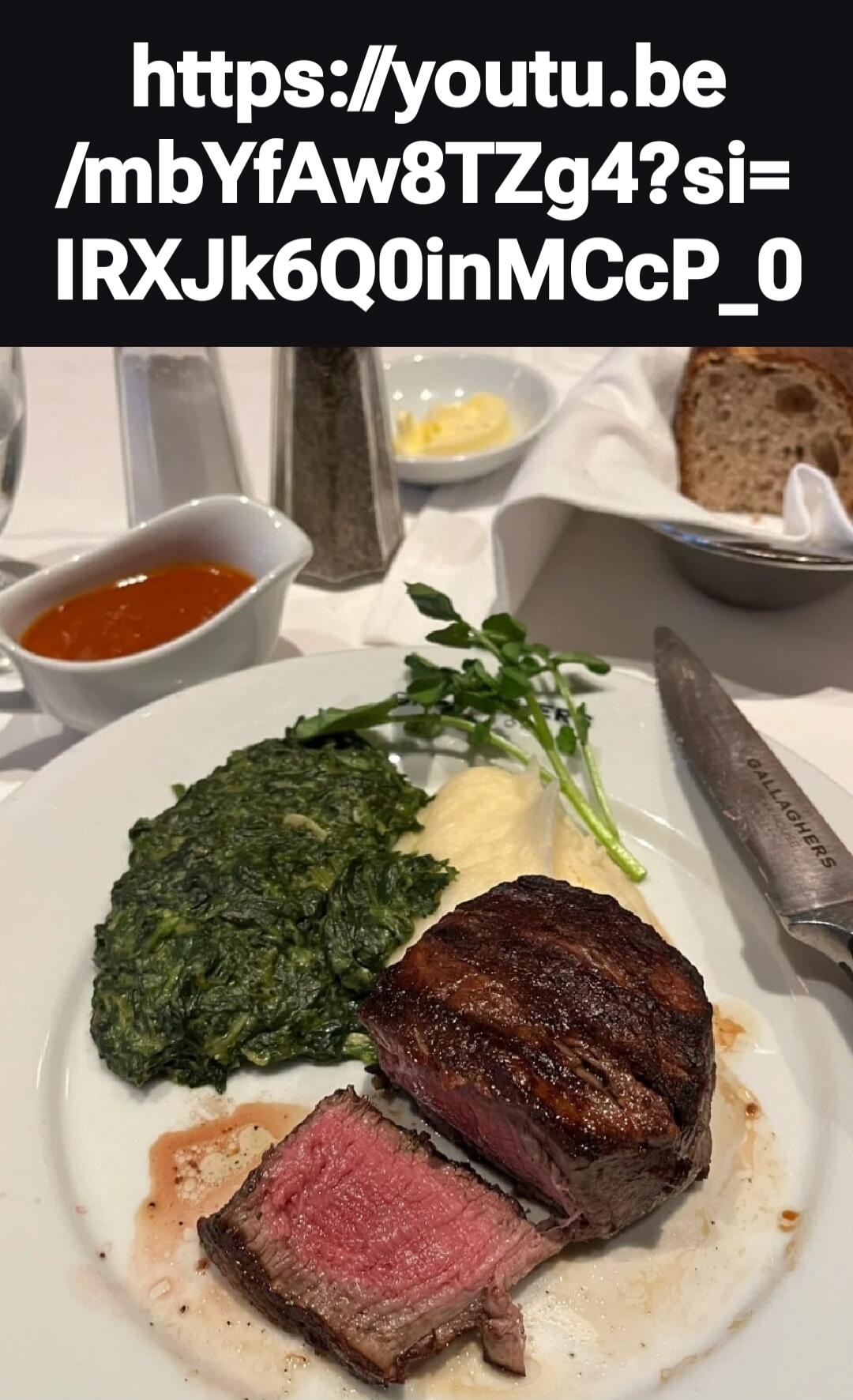 https://youtu.be/mbYfaw8TZg4?si=IRXJk6QoinMccP_0
A plated meal with a medium-rare steak, greens (spinach or kale), mashed potatoes, a small sauce cup, and slice of bread in the background.