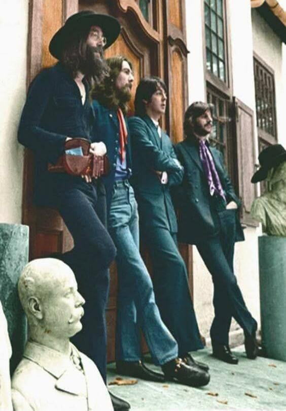 The Beatles standing outside a building.