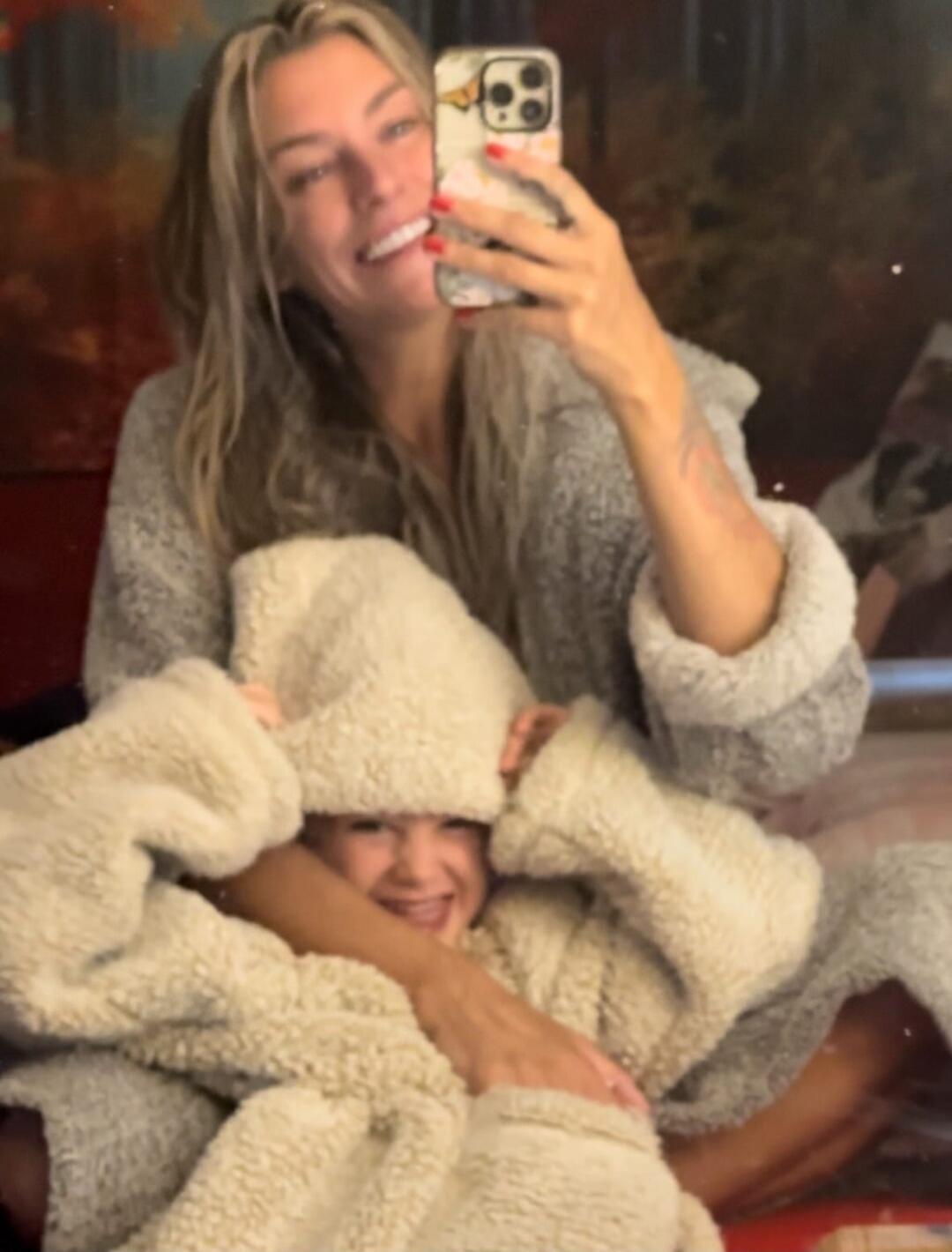 Two people wearing fluffy robes posing for a selfie; the smaller person making a silly face.