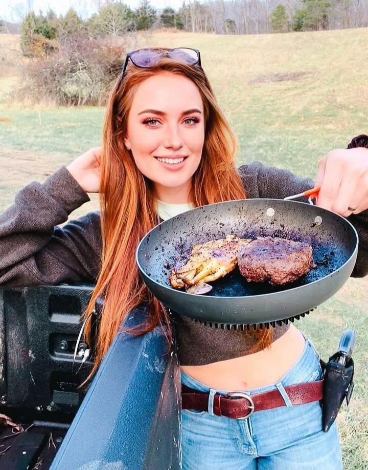 A woman is holding a frying pan with food in it.