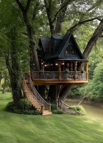 A beautiful treehouse nestled among lush green trees, featuring a winding wooden staircase and a balcony overlooking a serene river.