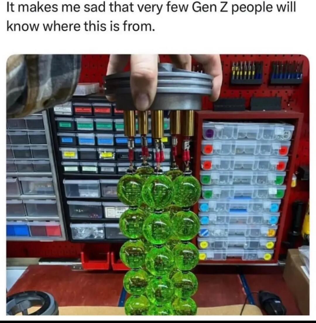 It makes me sad that very few Gen Z people will know where this is from. A hand holds a device with multiple green, glowing orbs, resembling plasma grenades from the Halo video game series, in a workshop setting.