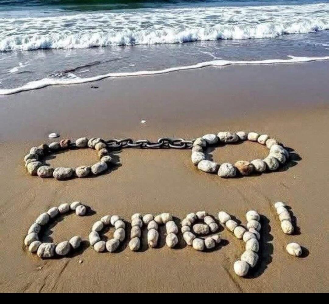 Handcuffs made of stones and a chain on the sand. Below them, the name 'Comey!' is spelled out with stones.