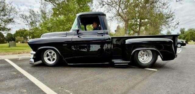 A black vintage pickup truck parked in a parking lot.