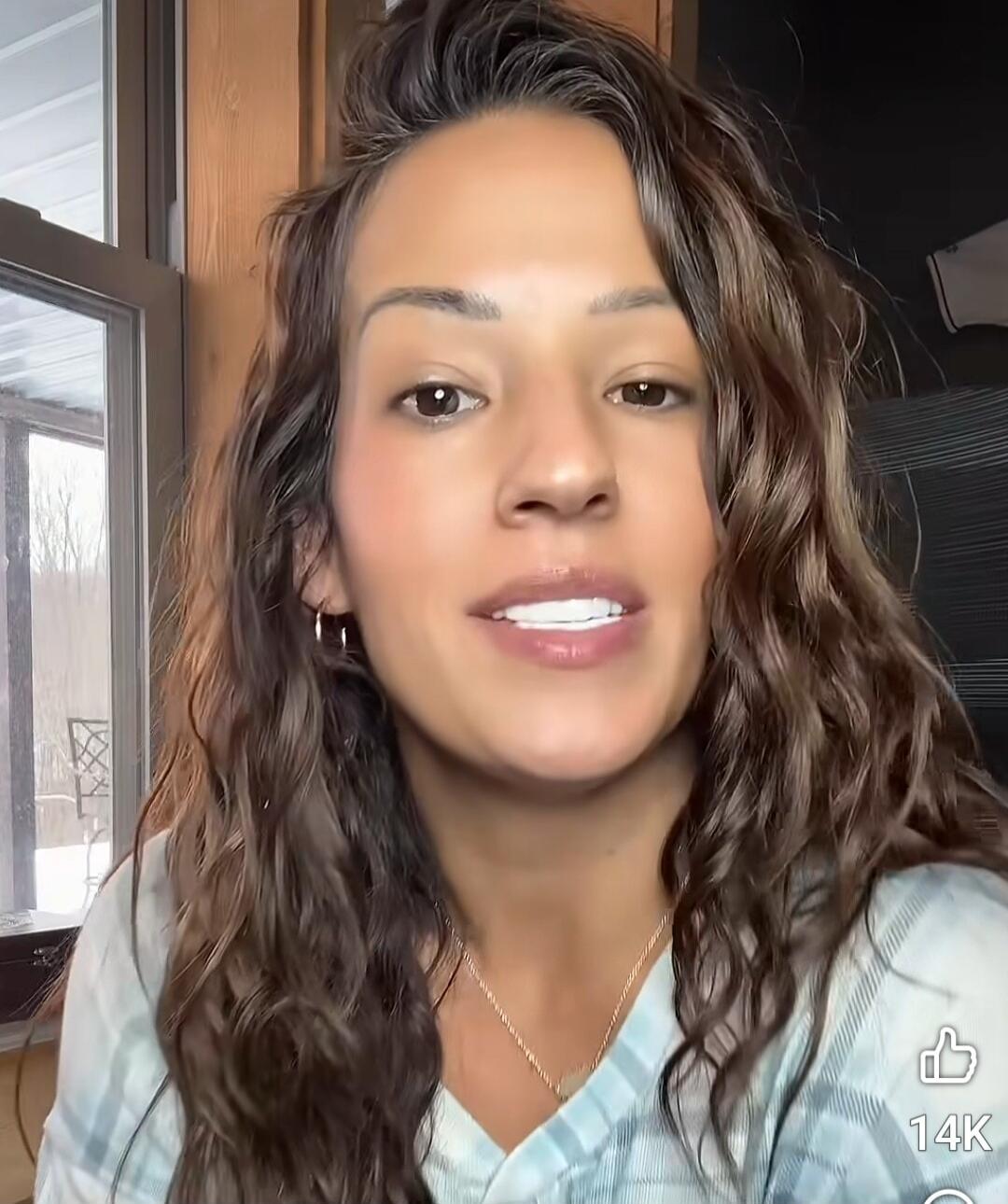 The woman is speaking to the camera in a casual setting.