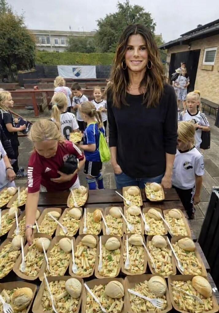 Sandra Bullock is seen serving pasta to young soccer players.