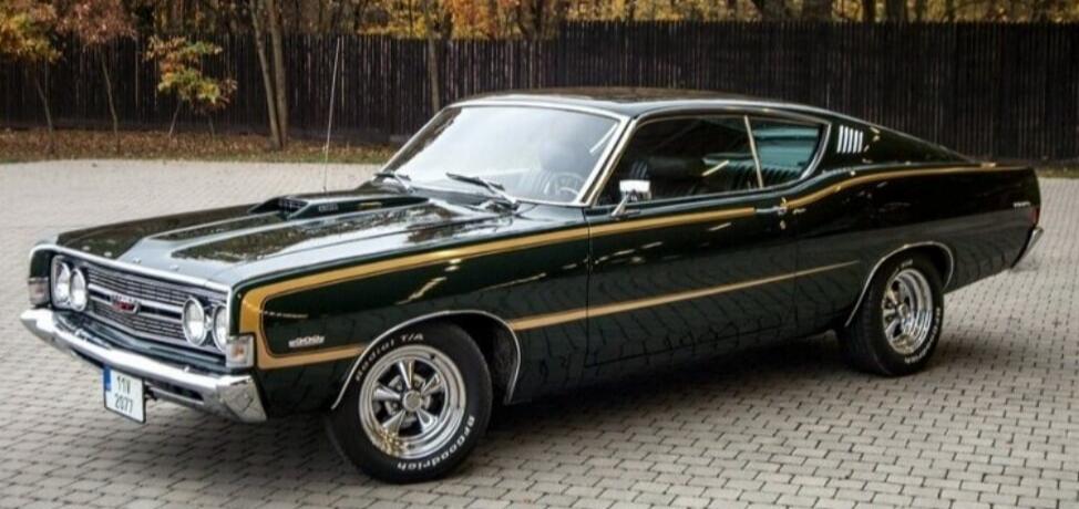 A dark green vintage muscle car parked on a paved surface.