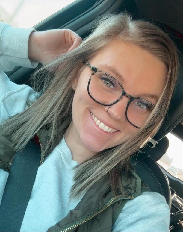 Smiling young woman wearing glasses in a car.