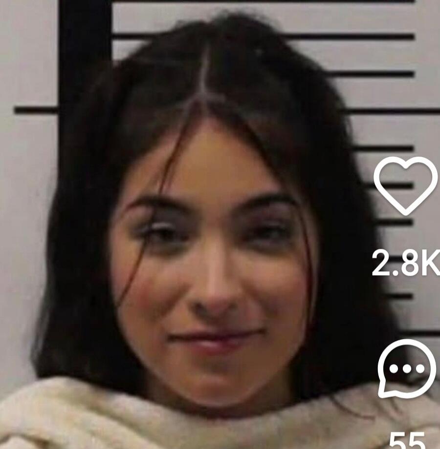 A young woman with dark hair is smiling, posing against a background that resembles a height chart, often seen in mugshots. Social media engagement numbers are visible: 2.8K likes and 55 comments.