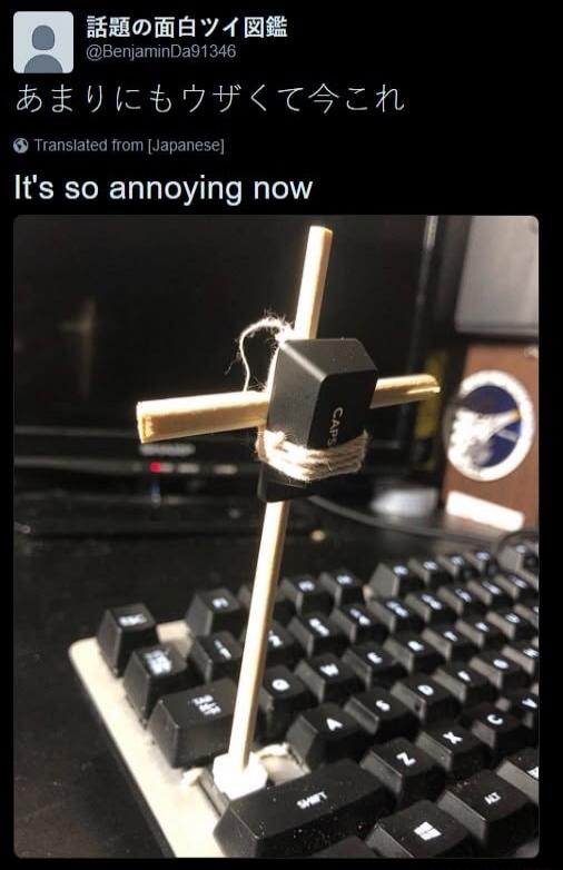A CAPS lock key is tied to a small wooden cross and inserted into a keyboard, holding the key down. The accompanying tweet text, translated from Japanese, says: 'It's so annoying now'.