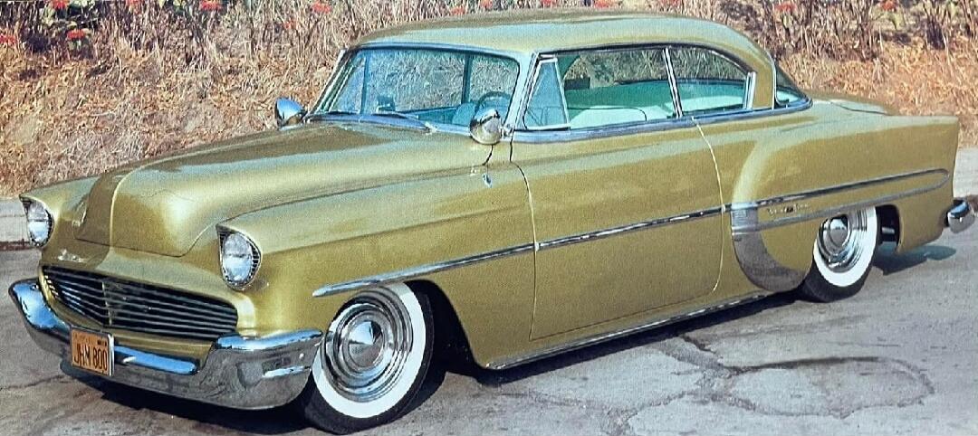 Gold vintage car with white-wall tires parked on a road